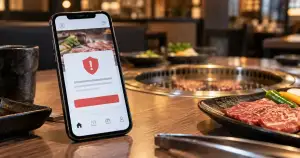 焼肉店のテーブル上に置かれたスマートフォンにセキュリティ警告が表示されている様子
